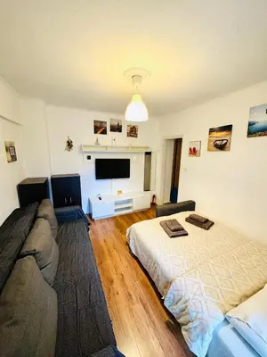 a bedroom with a bed and a couch and a flat screen tv at Athenian Riviera beach apartment in Athens