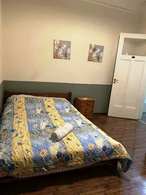 a bedroom with a bed with a blue and yellow quilt at Private room for 3 in a dorm 5' from metro in Athens