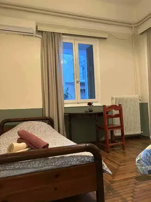 a bedroom with a bed and a desk and a window at Private room for 3 in a dorm 5' from metro in Athens