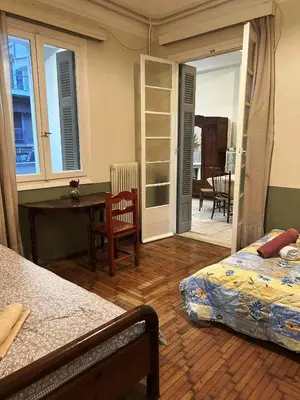 a bedroom with a bed and a desk and a table at Private room for 3 in a dorm 5' from metro in Athens