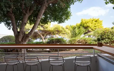 a group of chairs on a balcony with trees at Thalè Residence Varkiza in Vari