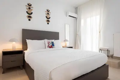 a bedroom with a large white bed and a window at Thalè Residence Varkiza in Vari