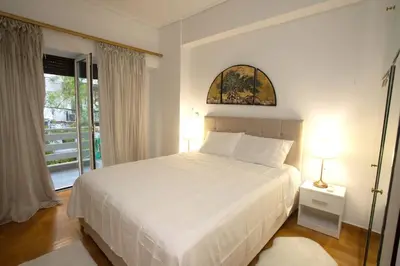 a bedroom with a white bed and a window at Kassandra lovely floor appartment in Patriarchou Ioakim the heart of Kolonaki in Athens