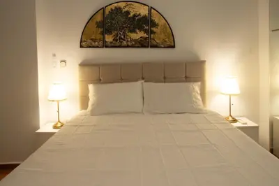 a bedroom with a large white bed with two lamps at Kassandra lovely floor appartment in Patriarchou Ioakim the heart of Kolonaki in Athens