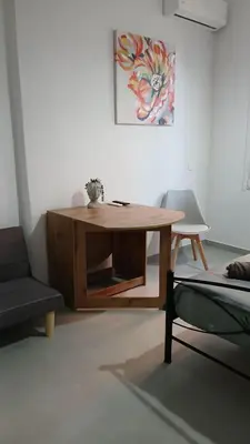 a living room with a wooden table and a chair at Athens Apartments, Piraeus Port in Athens