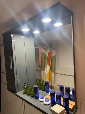 a bathroom mirror with blue and green bottles on a counter at illusion 2 in Piraeus