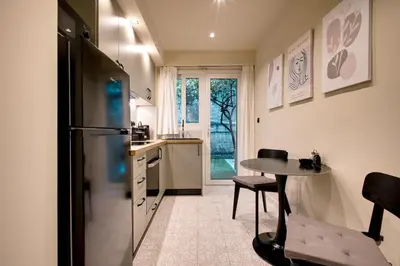a kitchen with a refrigerator and a table in it at Sweet Dispotition-Modern ground flat next to metro in Athens