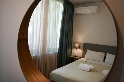 a mirror in a bedroom with a bed and a window at Tsakalof Luxe by Zeus Suites in Athens