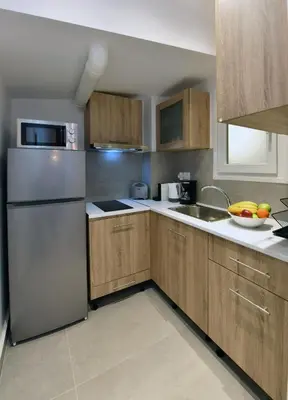 a kitchen with wooden cabinets and a stainless steel refrigerator at Hidden Paradise at Kolonaki in Athens