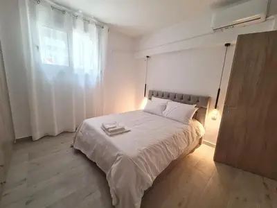 a bedroom with a bed with white sheets and a window at Family apartment at the center of Piraeus in Piraeus