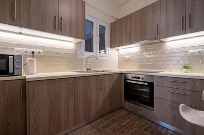 a kitchen with wooden cabinets and a sink and a microwave at Nea Smyrni 1 BDRM - Links To City Center by ΜΡS in Athens