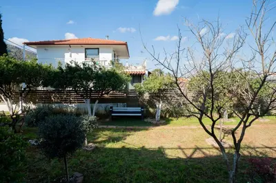 a white house with a bench in a yard at Livingstone House in Porto Rafti
