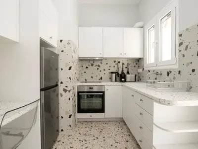 a white kitchen with white cabinets and a refrigerator at Apartment Athen von unserem Haus aus- wenige Schritte von der Akropolis entfernt by Interhome in Athens