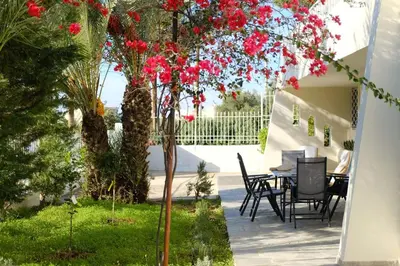 a patio with a table and a tree with red flowers at Apartment Theros near the beach in Anavissos