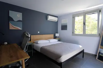 a bedroom with a bed and a desk and a window at Apartment Theros near the beach in Anavissos
