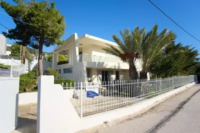 a white fence in front of a house at Apartment Theros near the beach in Anavissos