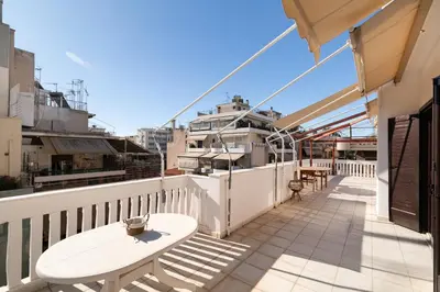 a balcony with a table and chairs on a building at Seaside Dublex with 2 Large Terraces Walk to the Beach in Piraeus
