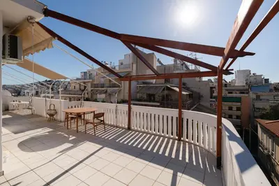 a patio with a table and chairs on a balcony at Seaside Dublex with 2 Large Terraces Walk to the Beach in Piraeus