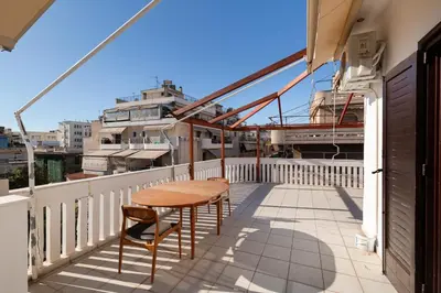 a balcony with a wooden table and chairs on it at Seaside Dublex with 2 Large Terraces Walk to the Beach in Piraeus