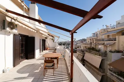 a balcony with a wooden table and chairs at Seaside Dublex with 2 Large Terraces Walk to the Beach in Piraeus