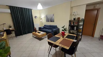 a living room with a table and a blue couch at Piraeus Gate - PS5 in Piraeus