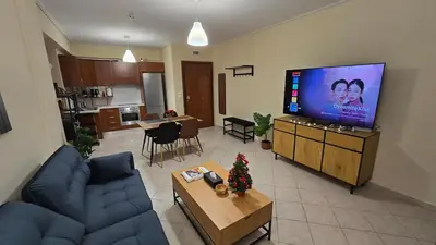 a living room with a blue couch and a television at Piraeus Gate - PS5 in Piraeus