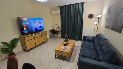a living room with a blue couch and a tv at Piraeus Gate - PS5 in Piraeus