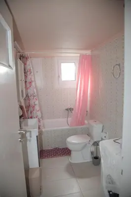 a bathroom with a white toilet and a pink shower curtain at Casa Urbana in Athens
