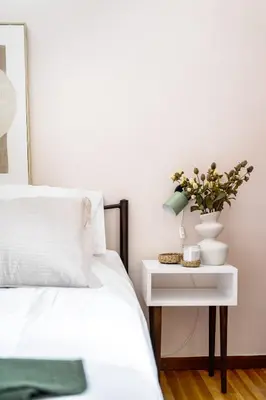 a bed with a table with a vase of flowers on it at Elegant City Retreat with Two Balconies in Athens