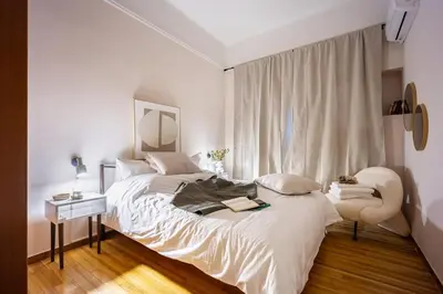 a bedroom with a large bed and a chair at Elegant City Retreat with Two Balconies in Athens