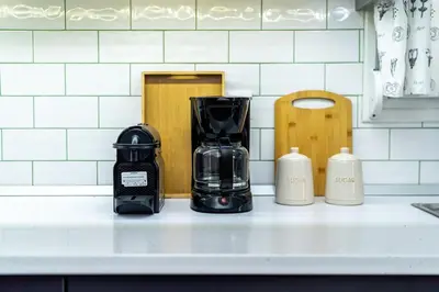 a coffeemaker sitting on a kitchen counter with three bottles at Elegant City Retreat with Two Balconies in Athens