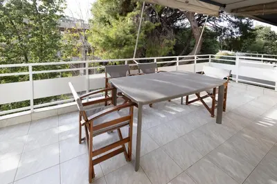 a wooden table and chairs on a balcony at Seaside Home in Porto Rafti