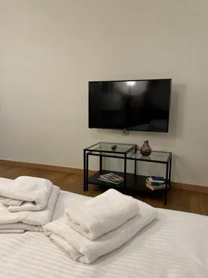 a bedroom with two white towels on a bed with a tv at Urban Muse VI - Archaeological Museum of Athens in Athens