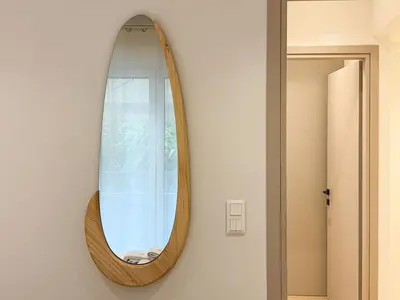 a wooden mirror hanging on a wall next to a door at Elegant Living in Glyfada Center in Athens