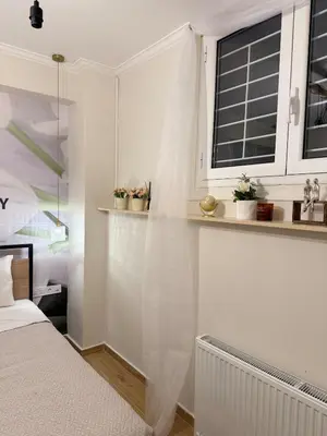 a white bedroom with a bed and a window at Paula Acropolis Thissio in Athens