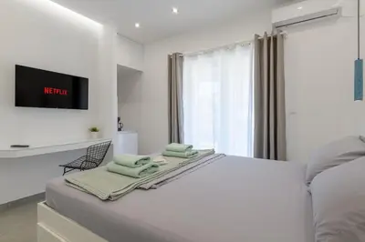 a white bedroom with a bed and a tv at NEW Dodekanisou 53 Glifada in Athens