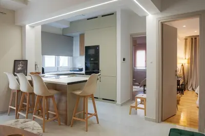 a kitchen with white cabinets and bar stools at Valtinon Smart Corner in Athens