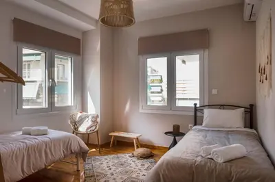 a bedroom with two beds and two windows at Valtinon Smart Corner in Athens