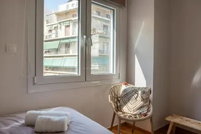 a bedroom with a bed and a window and a chair at Valtinon Smart Corner in Athens