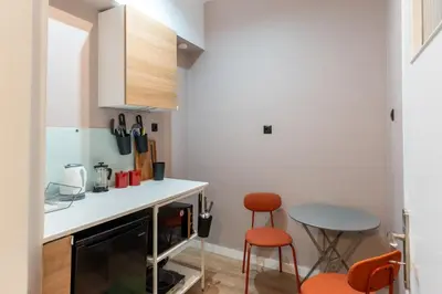 a small kitchen with orange chairs and a table at Athenian Bliss Spotless Nea Smyrni WiFi Studio in Athens