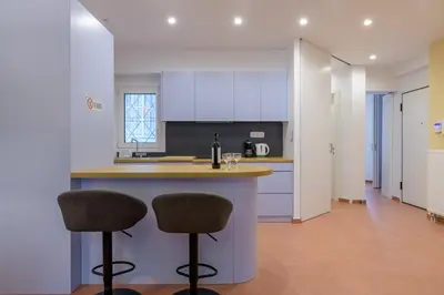 a kitchen with white cabinets and two bar stools at Acropolis walking distance apartment in Athens