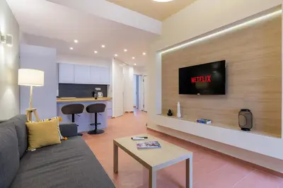 a living room with a couch and a tv on a wall at Acropolis walking distance apartment in Athens