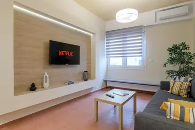 a living room with a couch and a tv on a wall at Acropolis walking distance apartment in Athens