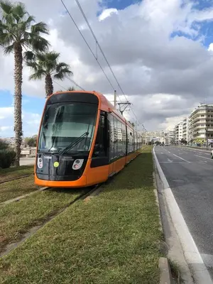 an orange train on the tracks next to a street at Sweet Apartment By The Sea in Athens