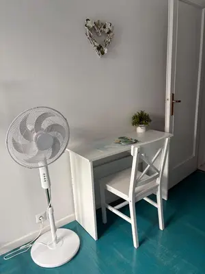 a white desk with a fan and a table with a chair at Sweet Apartment By The Sea in Athens