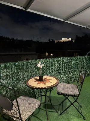 a table with two chairs and a vase of flowers on a patio at Luxury Retreat with Iconic Acropolis View Koukaki in Athens