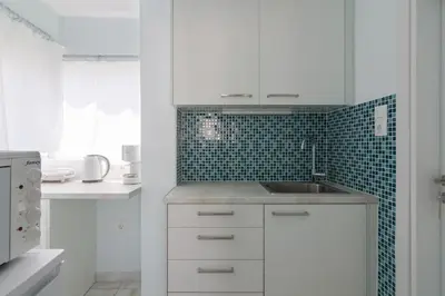 a white kitchen with a sink and green tiles at Luxury Retreat with Iconic Acropolis View Koukaki in Athens