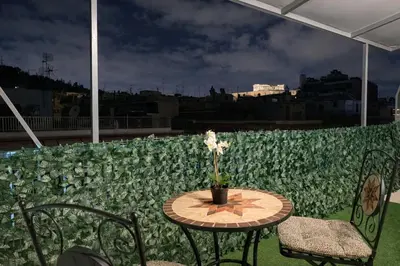 a table with a flower in a vase on a roof at Luxury Retreat with Iconic Acropolis View Koukaki in Athens
