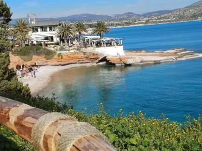 a view of a beach with palm trees and a building at varkiza luxury 2BD apartment in Vari
