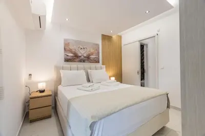a white bedroom with a large bed with white sheets at varkiza luxury 2BD apartment in Vari